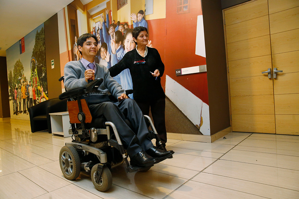 Persona con discapacidad en silla de ruedas junto a otra persona caminando